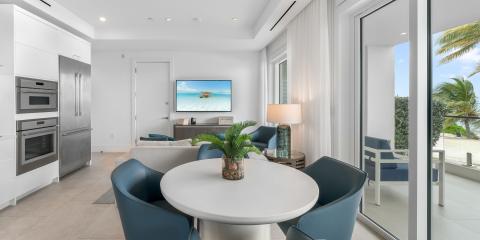 This image shows a modern and elegantly designed interior space that seems to serve multiple purposes, blending elements of a kitchen, dining area, and living room in an open floor plan