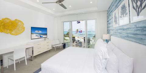 The image shows a modern, beautifully appointed bedroom with a coastal beach theme