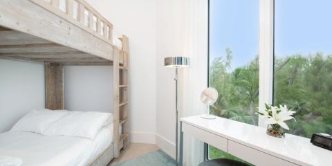 This image features a modern, well-lit room with a large window providing a view of lush green foliage outside