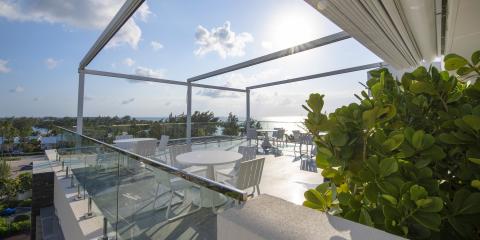 This image shows a spacious terrace setting with a panoramic view of a coastal landscape during daytime, under clear skies with minimal cloud cover