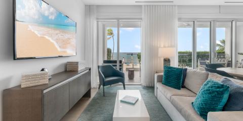 This image shows a modern and stylishly decorated living room with a view of a beach