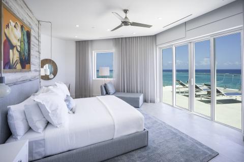 This image features a modern and elegant bedroom with a beautiful ocean view