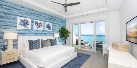 This image features a stylish modern bedroom with a stunning ocean view