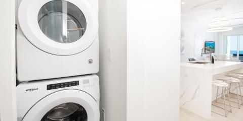 This image showcases a modern home interior featuring a laundry setup on the left, with a stacked washing machine and dryer by Whirlpool, and a kitchen area on the right
