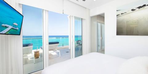 This image shows a luxurious and modern bedroom with a beautiful ocean view