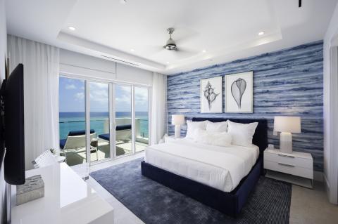 This image shows a modern and luxurious bedroom with a stunning ocean view