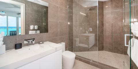 This image shows a modern bathroom with a scenic view of the ocean through a large window