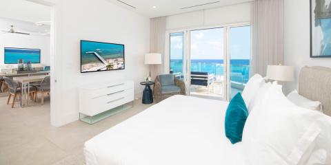 This image shows a modern, luxurious bedroom with a view of the ocean