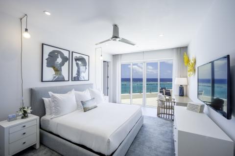 This image shows a modern, stylish bedroom with a remarkable ocean view