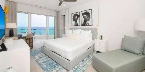 This image shows a well-lit, modern bedroom with an elegant interior and an ocean view