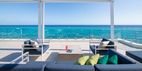 The image shows an elegant outdoor terrace with a stunning view of the ocean