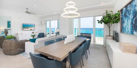 This image features a modern, stylish interior of a living and dining area with a stunning ocean view