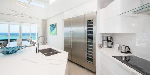 This image features a sleek, modern kitchen with a breathtaking ocean view