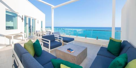 This image shows a luxurious outdoor terrace overlooking a beautiful, clear blue sea