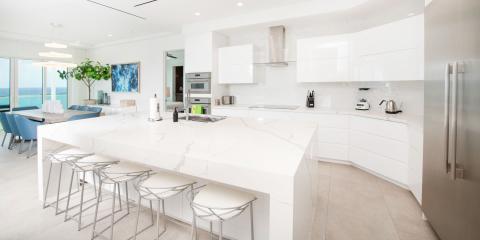 This image shows a modern, luxurious kitchen that flows into a dining area, all with an ocean view