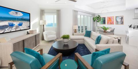 This image shows a modern, stylishly decorated living room with large windows and a view of the ocean
