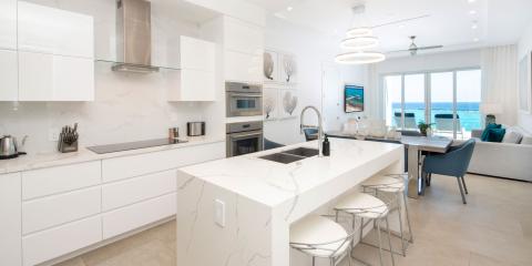 This is an image of a modern kitchen and an adjoining living room area with a coastal view