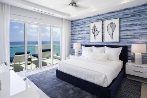 This image depicts a modern and luxurious bedroom with a breathtaking ocean view
