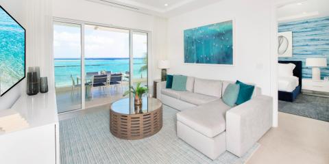 This image shows a modern and stylish beachfront living room with a panoramic ocean view