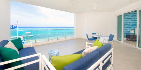 This image shows an elegantly furnished indoor balcony or sunroom that opens up to a stunning seaside view