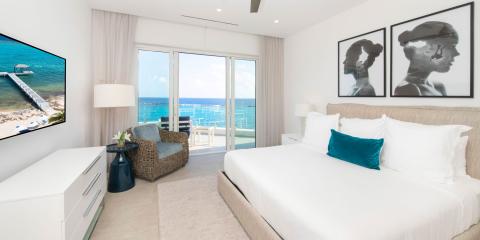 This is an image of a modern and bright bedroom with a beachfront view