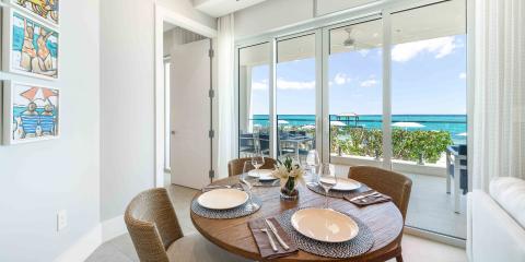 This image shows a beautifully set dining area in a room with a stunning ocean view