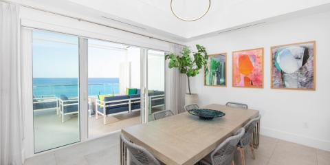 This is an image of a bright, modern dining room with a scenic view of the ocean