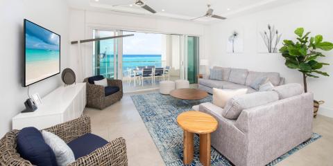 The image displays a modern living room with a beachfront view