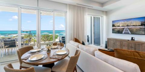 The image shows a beautifully decorated beachfront apartment with a large, clear view of the turquoise sea
