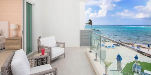 The image shows a luxurious outdoor terrace of a hotel room overlooking an ocean