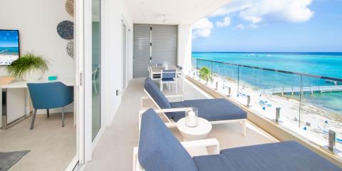 The image shows a luxuriously appointed balcony with a beautiful view of a beach