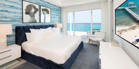 The image shows a modern and luxurious bedroom with a large comfortable bed with white linens