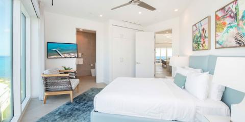The image shows a modern and stylish bedroom featuring a large bed with white bedding and a light blue headboard