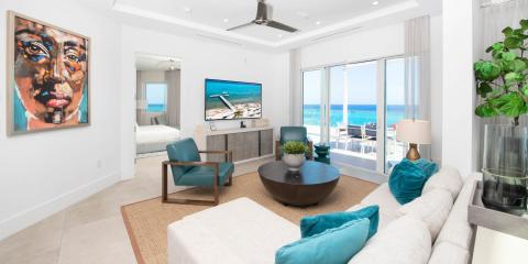 The image shows a modern, bright living room overlooking a beach