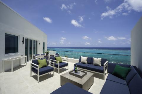 The image shows a modern rooftop terrace overlooking a breathtaking ocean view