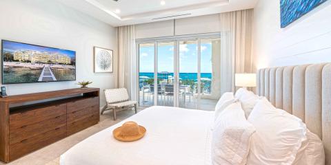 This image displays a luxurious bedroom with a stunning ocean view