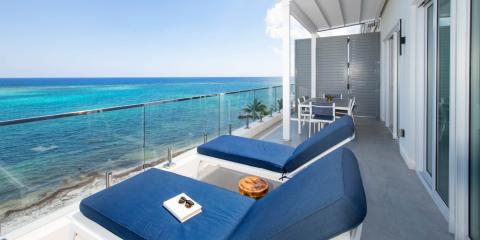 This image features a beautiful oceanfront balcony with a breathtaking view of a clear blue sea