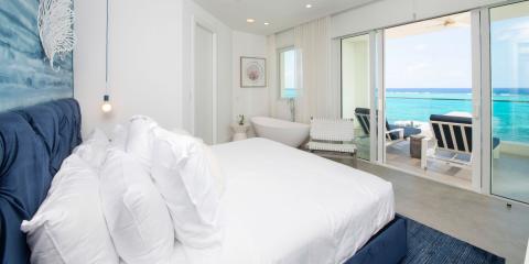 This image features a luxurious bedroom with a beachfront view