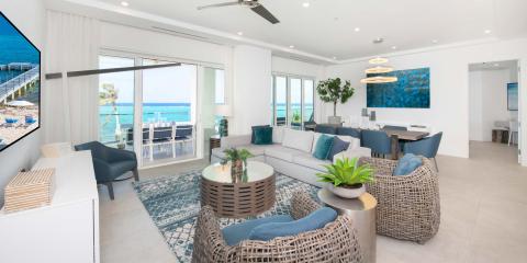This image features a modern and luxurious beachfront living room with expansive views of the ocean