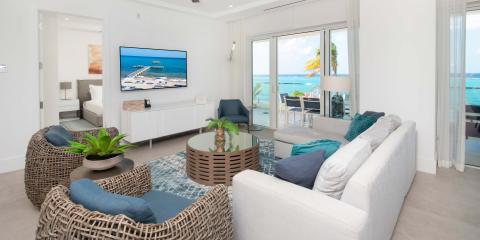 This image showcases a modern beachfront living room that opens directly to a stunning ocean view