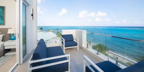This image shows a beautiful coastal scene viewed from a balcony of a modern room or hotel suite