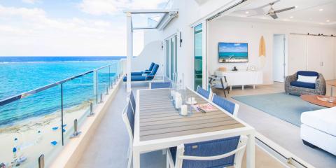 This image shows a luxurious balcony area and an adjacent interior living space of a high-end vacation property or resort