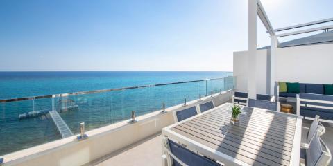 This image shows a luxurious balcony overlooking a picturesque blue sea
