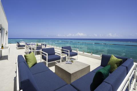 This image shows a luxurious outdoor terrace with a panoramic view of the ocean