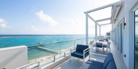 This image shows a luxurious seaside balcony overlooking a beautiful turquoise ocean