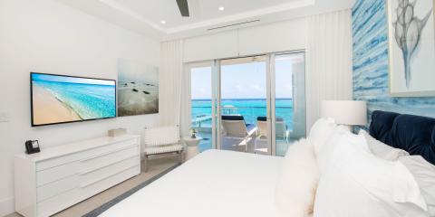 This image shows a modern and luxurious bedroom with large windows overlooking a stunning ocean view