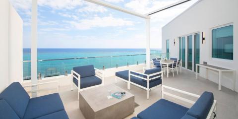 This image shows a modern and luxurious outdoor terrace of a home or hotel, with stylish outdoor furniture that includes sofas, chairs, and tables, all featuring clean, contemporary designs