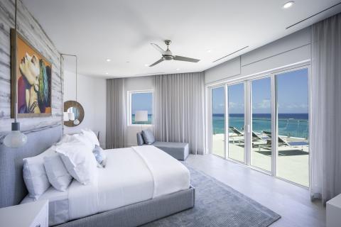 This image shows a modern and stylish bedroom with a scenic view of the beachfront