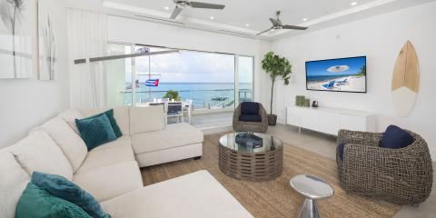 This image shows a modern, beachfront living room with a beautiful view of the sea
