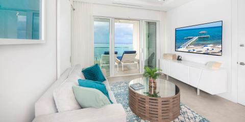This image shows a modern, bright living room with a coastal theme, overlooking a beautiful beach view